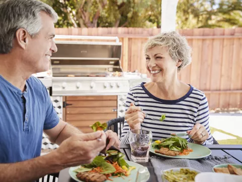 A couple eats a healthy meal together outside.