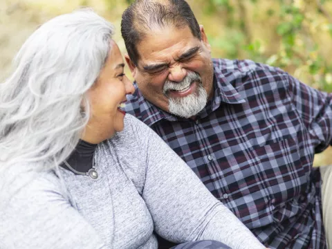 A couple laughs while on an outdoor picnic.