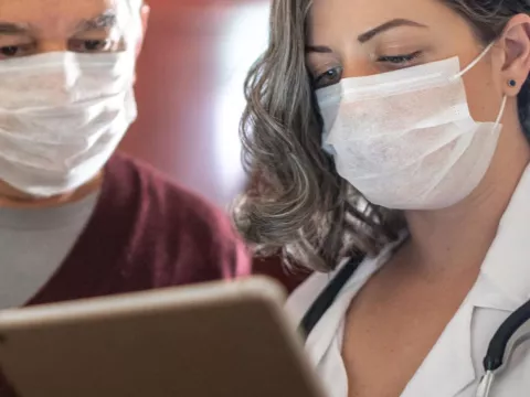 A doctor showing her patient something on her business tablet