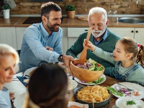 A family passing a salad at the dinner table.