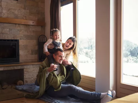 A young family plays together indoors by a window at home