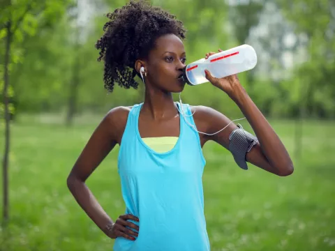 A woman taking a water break during her run.