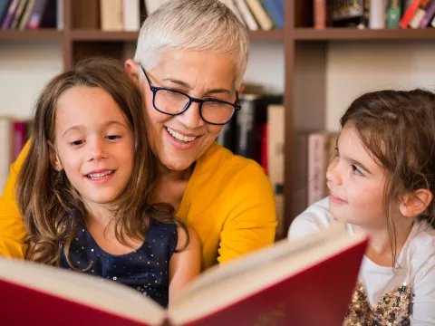 A grandmother reading to her granddaughters. 