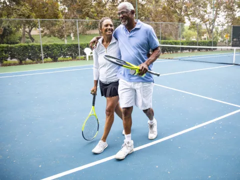 A happy couple plays a game of tennis.