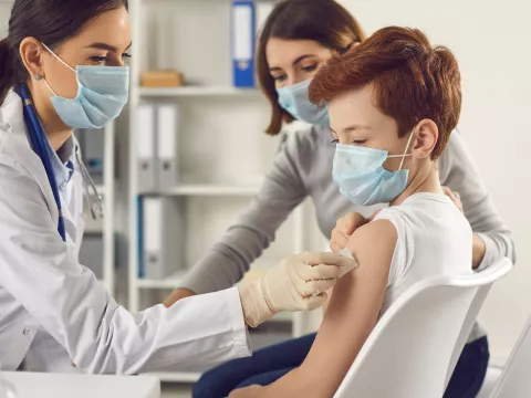 A teenager getting a vaccine shot by a doctor