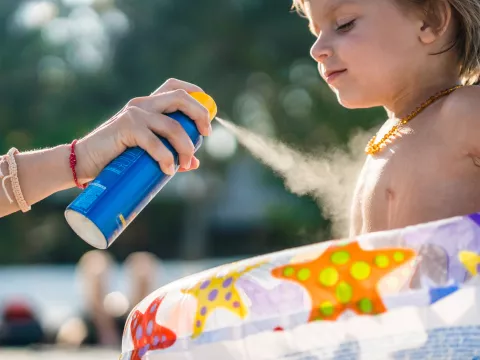 Little boy gets sunscreen protection from his mom at the beach