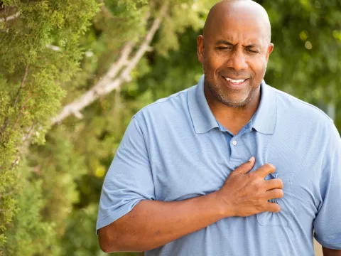 A man experiencing chest pain during a walk outdoors.