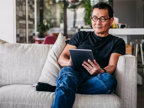 An asian man reading in his living room