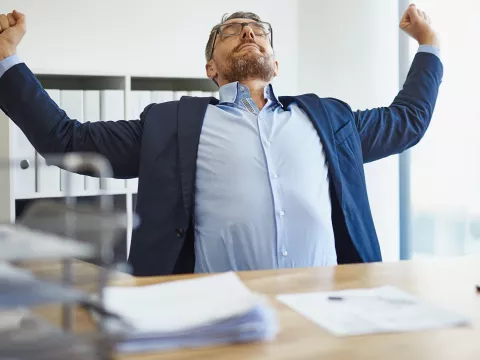 A man stretching at his desk.