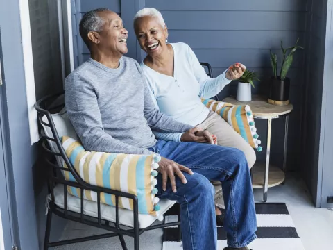 A couple laughing on their front porch together.