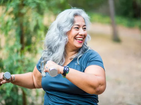 An overweight senior hispanic woman uses weights while she exercises