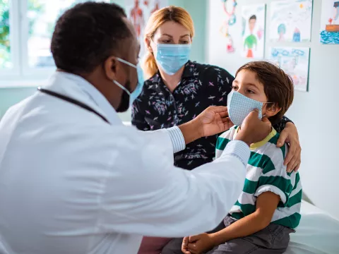 Mother and son at a doctor's office while wearing masks.