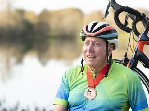 Man wearing a medal standing with his bike