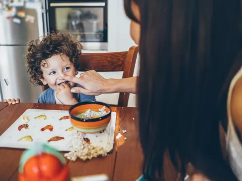 A young boy messily eats his breakfast