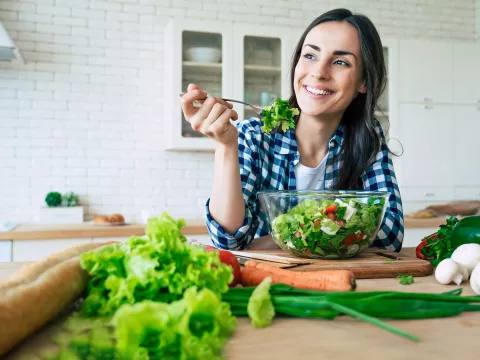 A woman eating a healthy, homemade salad.