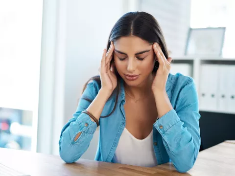 A woman with a headache massaging her temples.