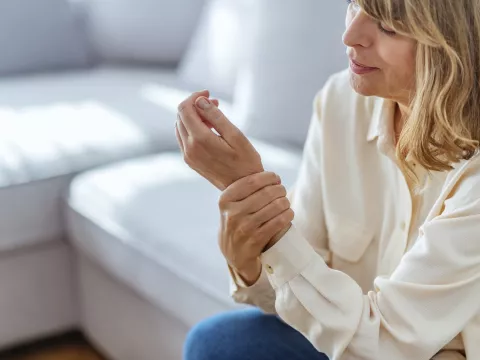 A woman with arthritis massages her hand.