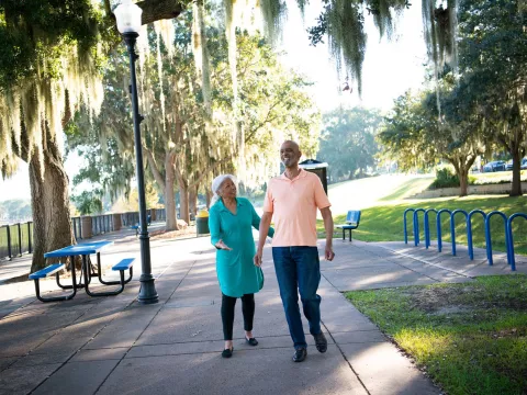 A Couple Walks Through a Park By a Lake in Clermont Florida, Laughing and Enjoying the Outdoors.