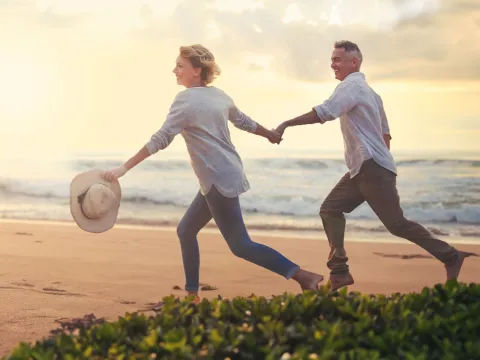 a couple running on the beach at sunset holding hands