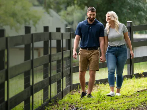 man and woman walking along a fence and smiling