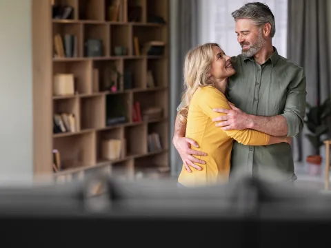 Man and woman hugging at home.