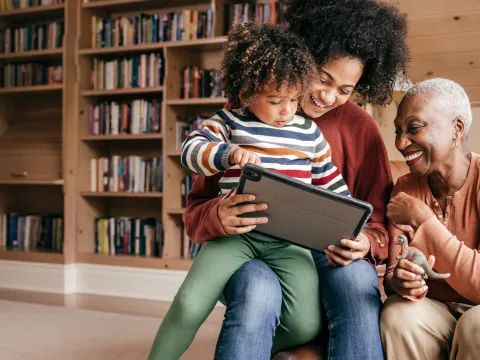 Mother, grandmother and child looking at a tablet at home.