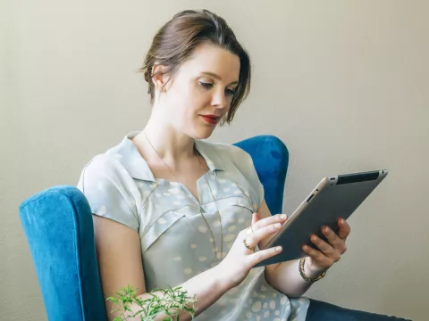 A young caucasian woman reads from her tablet indoors.