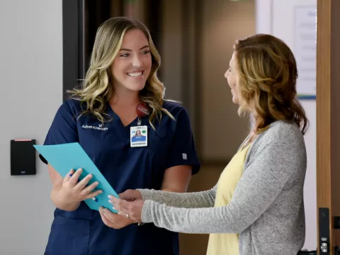 A Primary Care+ Nurse Goes Over Paperwork with a Smiling Patient