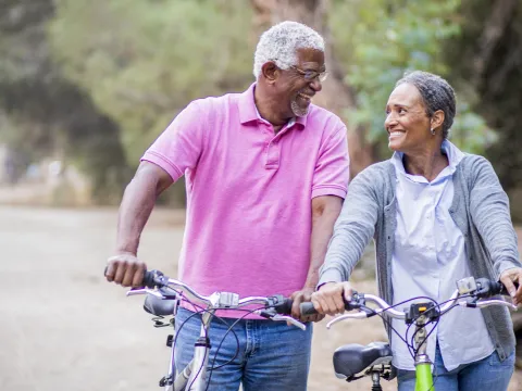 Older couple walking with bikes.