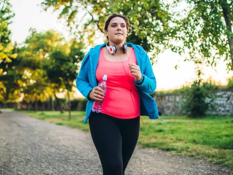 A woman running with headphones and a bottle of water