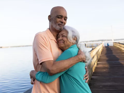 Senior couple hugging while on a dock at a lake.