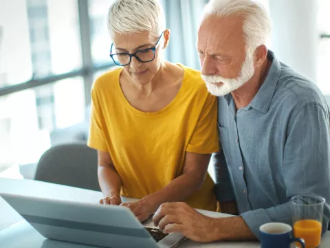 Senior couple viewing a laptop together at the kitchen counter