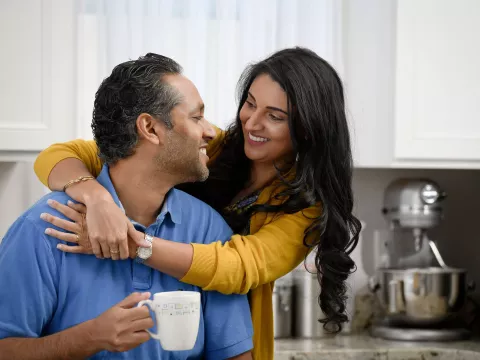 Happy couple embracing in the kitchen.