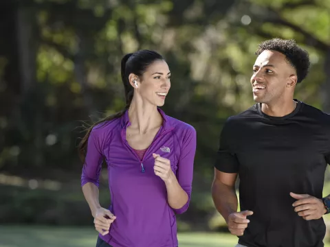 A Couple Runs Together in the Park While Sharing a Laugh