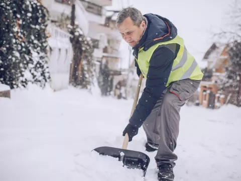 An older man shoveling snow.