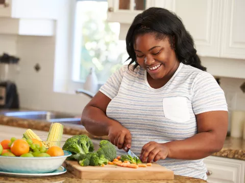 A woman chopping vegetables in the kitchen.