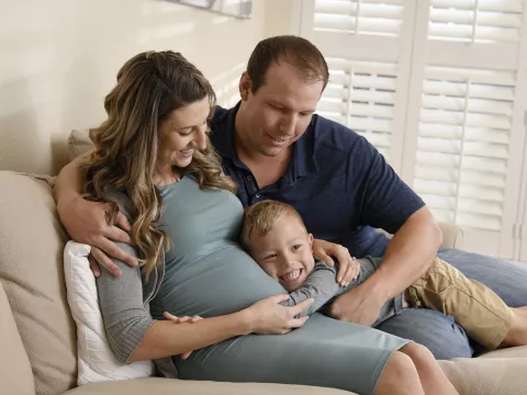 Pregnant mom hugging her family on the couch