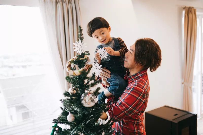 Father and son decorating a Christmas tree.