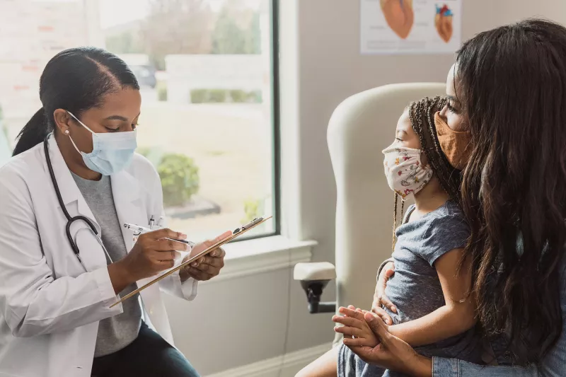 Doctor speaks to mother and child in a patient room.