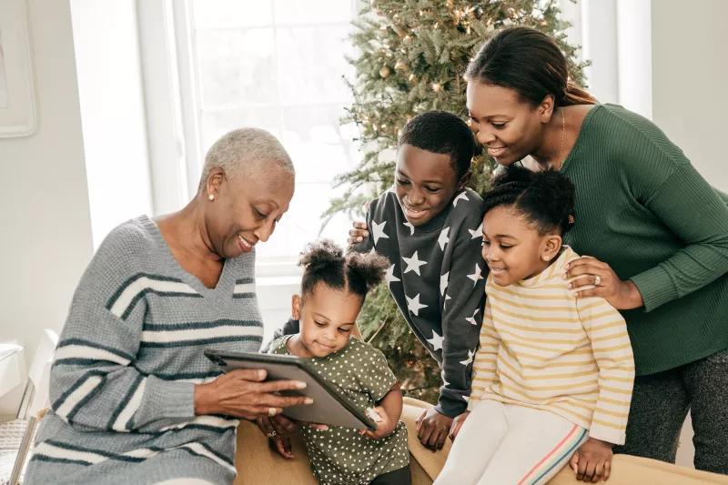 Family looking at photo album next to a Christmas tree