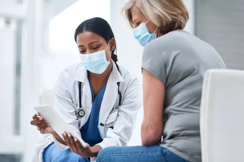 Doctor speaks to her middle aged female patient while going over some notes.