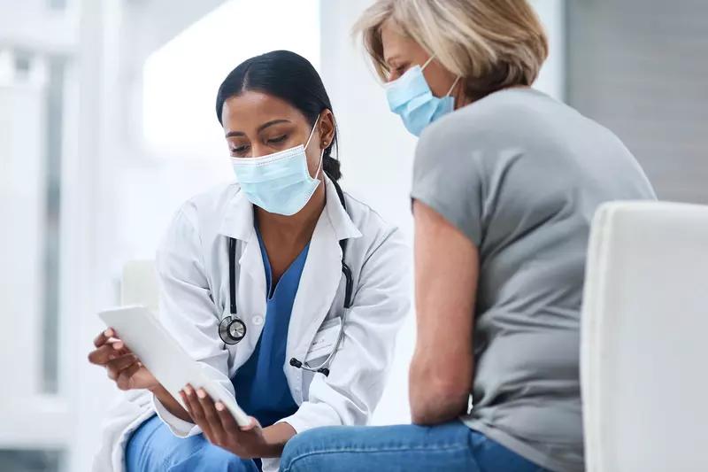 Doctor speaks to her middle aged female patient while going over some notes. 