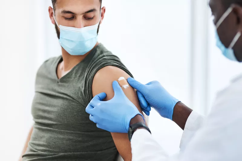 Medical professional putting a bandaid on a man after he received a covid-19 vaccine booster shot