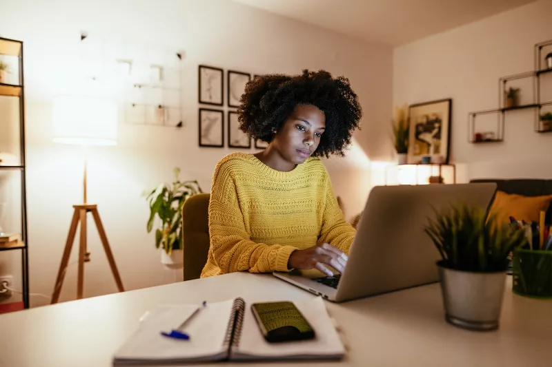 Woman looking at her laptop screen in a home office in the evening