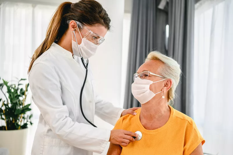 A doctor listens to a patient's breathing with a stethoscope