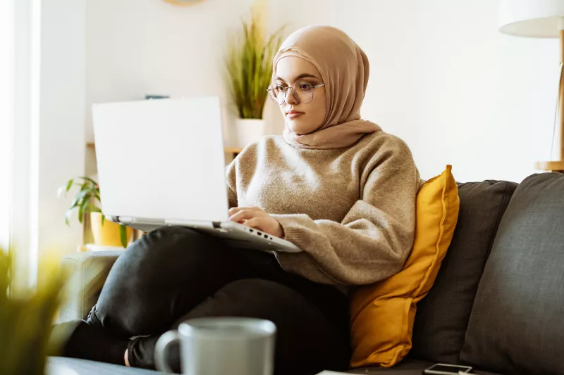 A Woman Looks at a Laptop Computer on Her Couch.