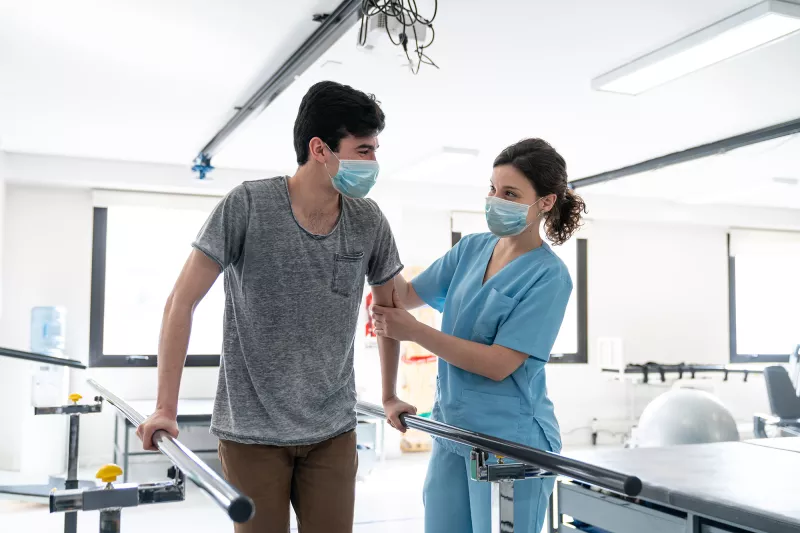 Physical therapist helping a patient through a walking exercise.