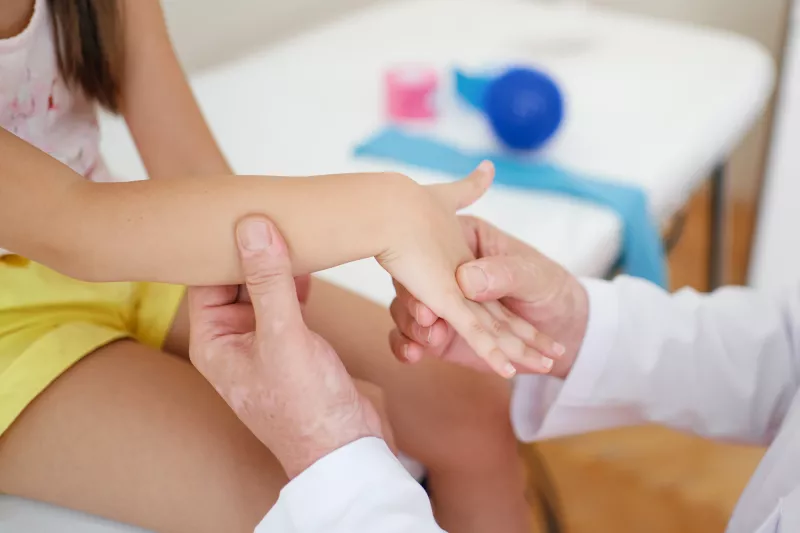 A Close Up of a Doctor Examining a Child Patient's Hand