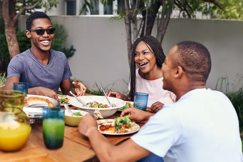 A Family Gathers Around a Outdoor Table to Enjoy a Meal.