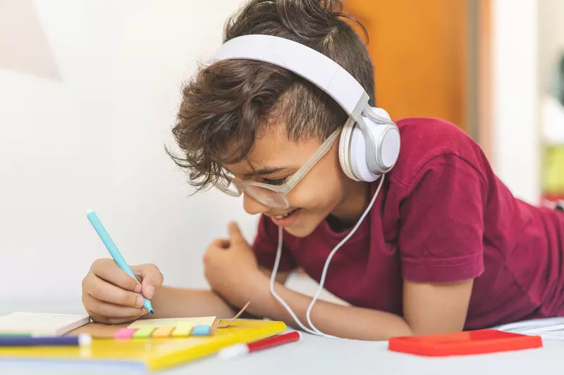 Boy working on schoolwork wearing headphones 